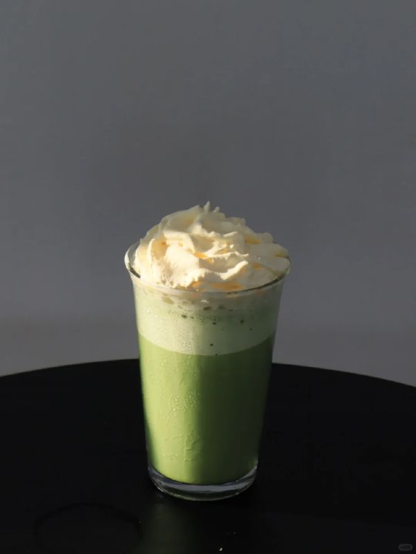 Jasmine matcha cream cap drink in a glass, topped with a tall swirl of whipped cream.