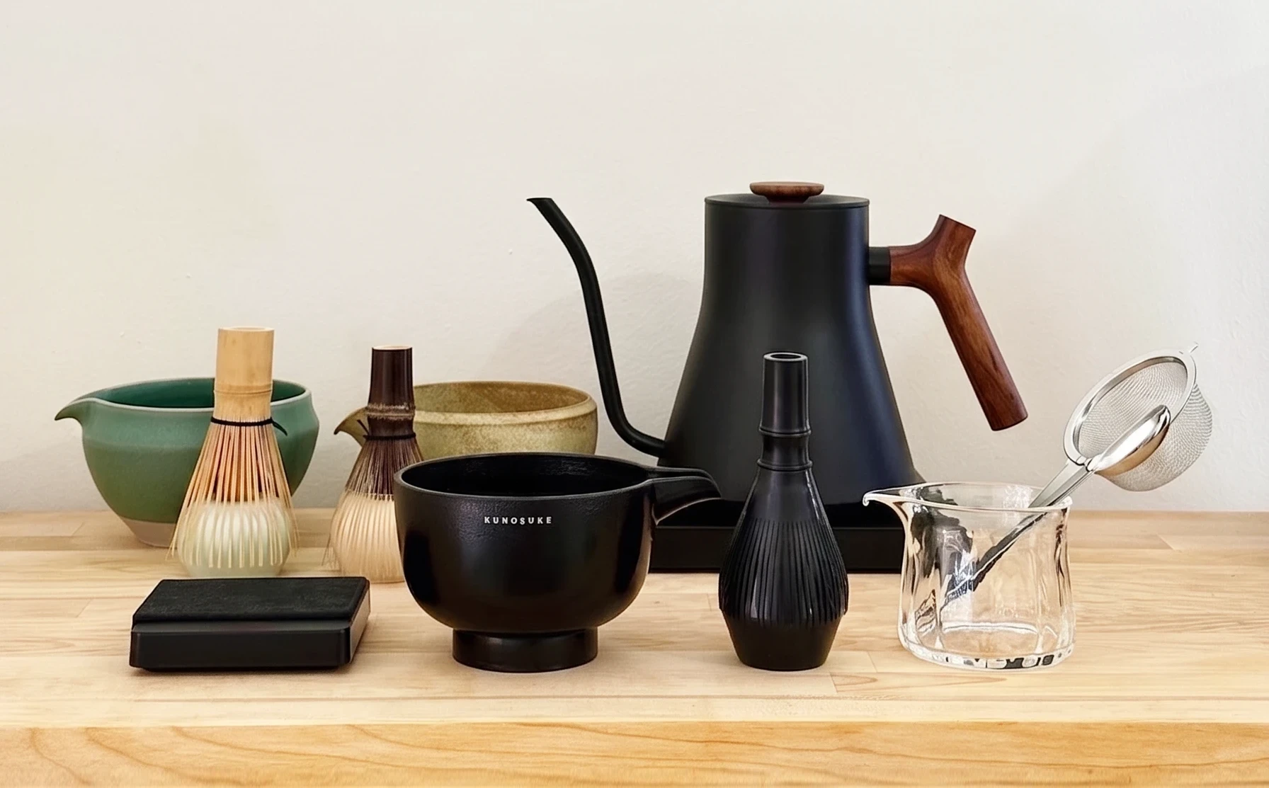 Essential matcha tools for beginners, including a chasen, chawan, chashaku, sifter, and whisk stand.
