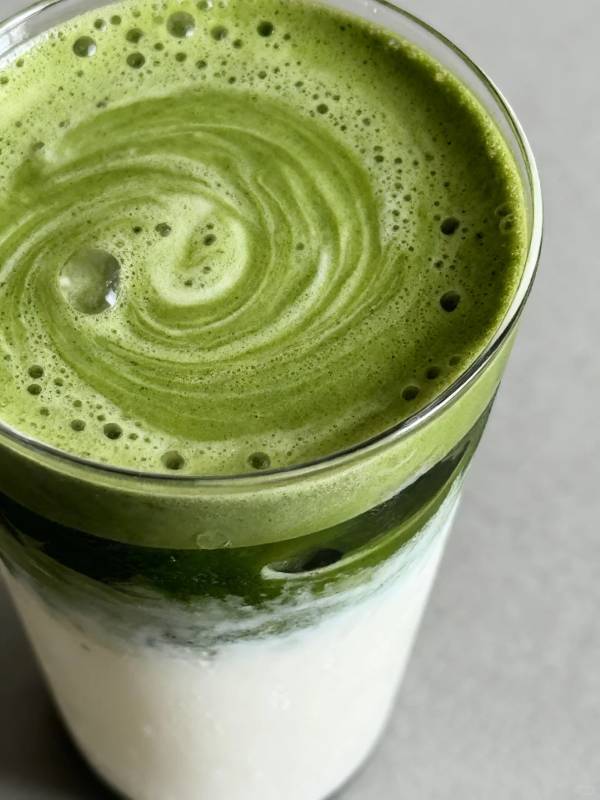 Close-up of thick coconut matcha latte showing foamy bright green matcha on top.